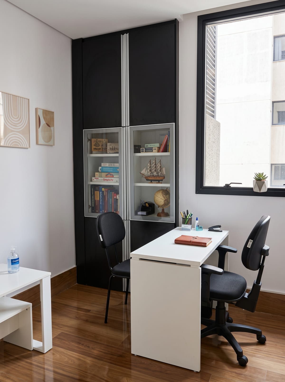 Sala de atendimento: mesa, duas cadeiras e estante de livros
